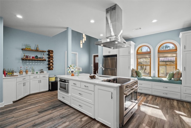 kitchen with stainless steel appliances, island exhaust hood, white cabinets, and an island with sink