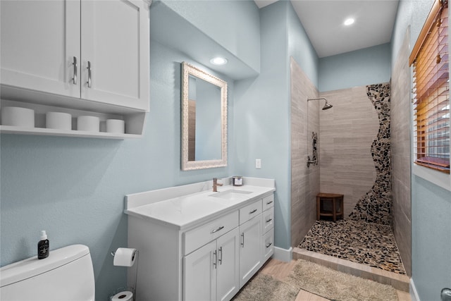 bathroom featuring toilet, vanity, and a tile shower