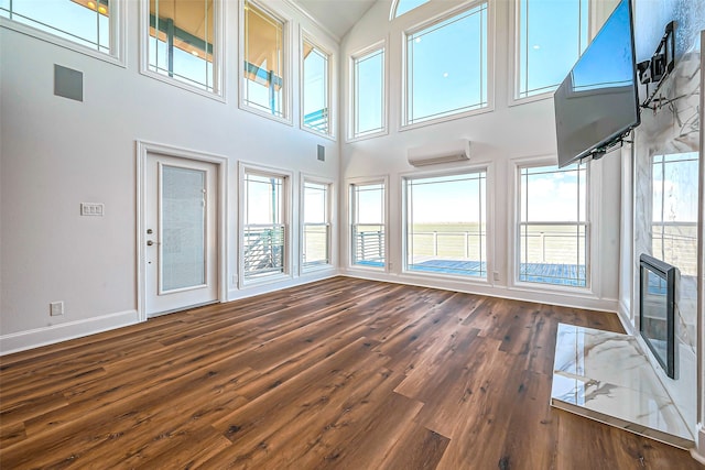 interior space featuring dark hardwood / wood-style flooring, a wall mounted AC, and a towering ceiling