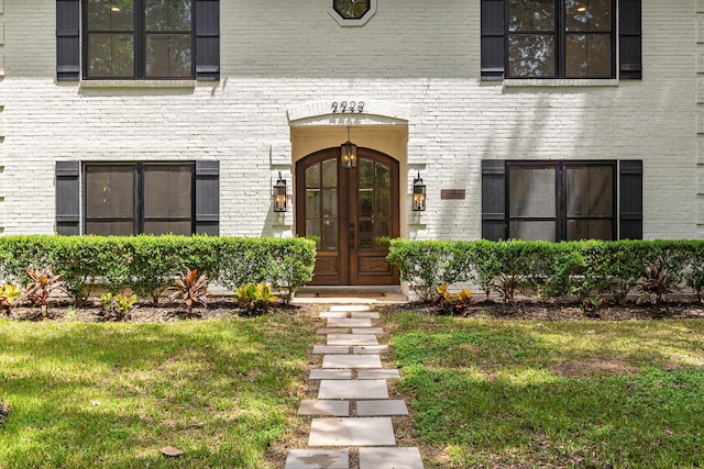 view of exterior entry with french doors and a lawn