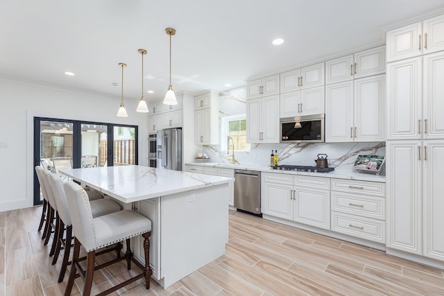 kitchen featuring sink, a center island, hanging light fixtures, stainless steel appliances, and decorative backsplash