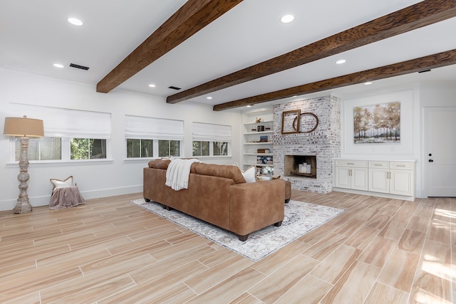 living room featuring built in shelves, beam ceiling, and a brick fireplace