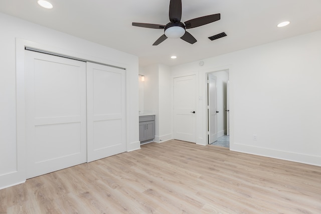 unfurnished bedroom with ceiling fan, ensuite bath, a closet, and light wood-type flooring