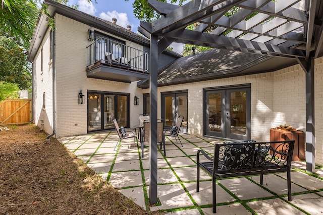 rear view of house with a pergola, a patio area, french doors, and a balcony