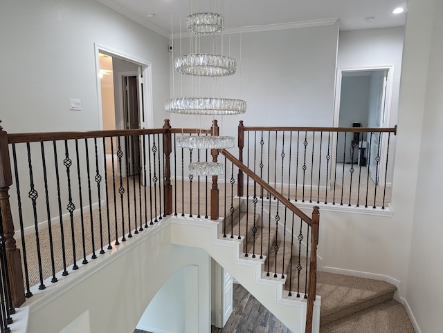 stairs with ornamental molding, hardwood / wood-style flooring, and an inviting chandelier