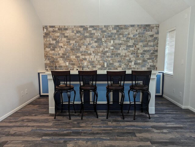 bar featuring dark wood-type flooring and vaulted ceiling