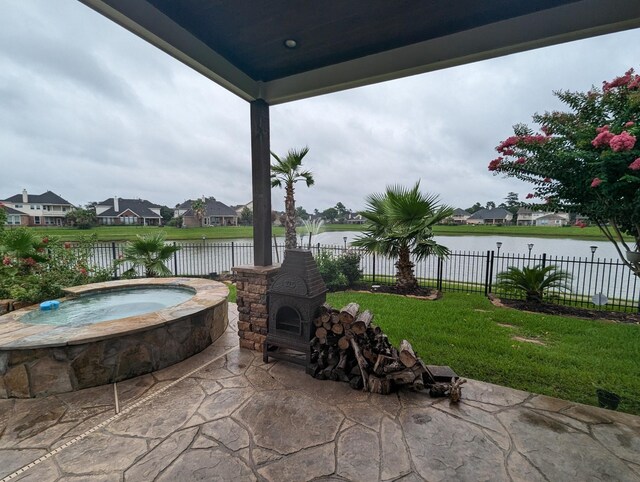 view of patio with a water view and an in ground hot tub