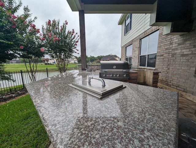 view of patio featuring exterior kitchen, a water view, and grilling area