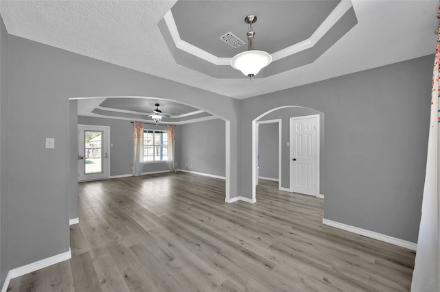 interior space featuring light wood-type flooring, a tray ceiling, a textured ceiling, and ceiling fan