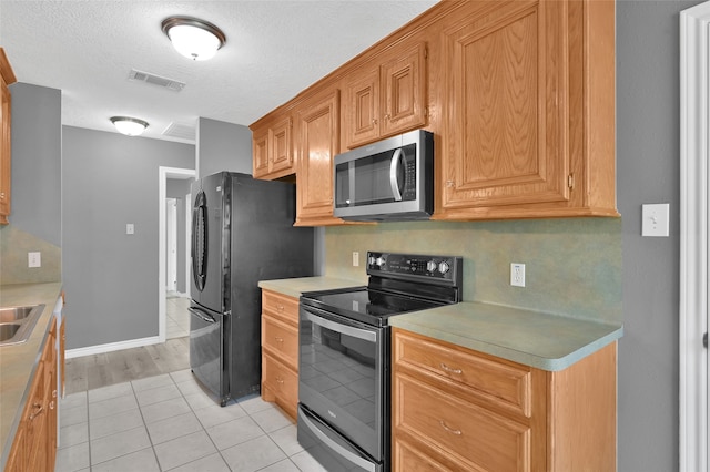 kitchen featuring light hardwood / wood-style floors, a textured ceiling, sink, and black appliances