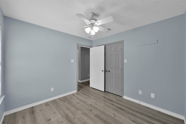 unfurnished bedroom with a textured ceiling, light hardwood / wood-style floors, ceiling fan, and a closet