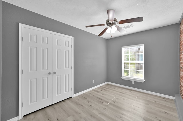 unfurnished bedroom featuring a closet, a textured ceiling, ceiling fan, and light hardwood / wood-style flooring