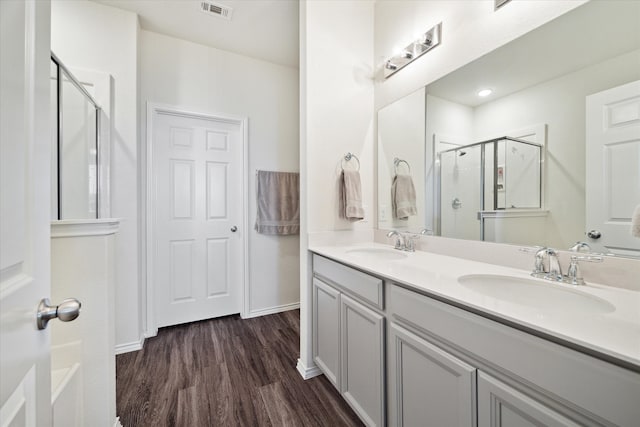 bathroom with hardwood / wood-style floors, vanity, and an enclosed shower