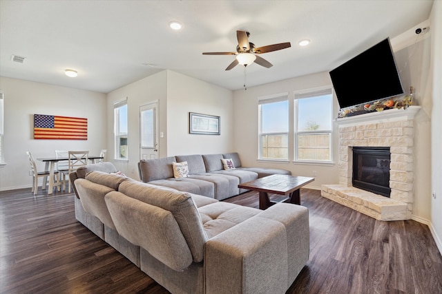 living room featuring a stone fireplace, ceiling fan, and dark hardwood / wood-style flooring