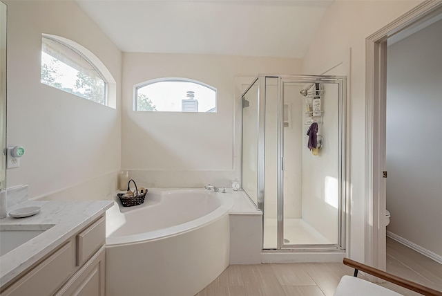 bathroom with vaulted ceiling, tile patterned flooring, shower with separate bathtub, and vanity