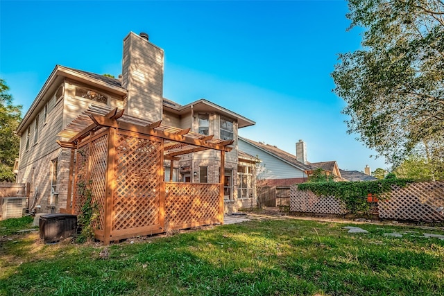 rear view of property featuring central AC unit, a pergola, and a yard