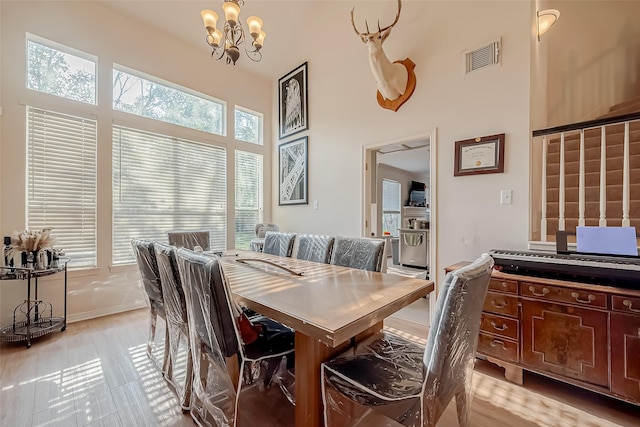 dining room with a high ceiling, light hardwood / wood-style flooring, and a notable chandelier