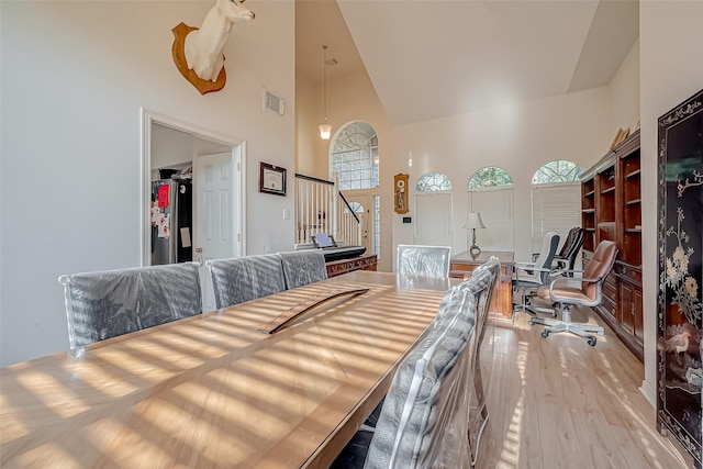 dining space featuring light hardwood / wood-style floors and high vaulted ceiling