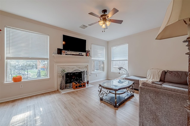 living room featuring ceiling fan, wood-type flooring, a premium fireplace, and ornamental molding