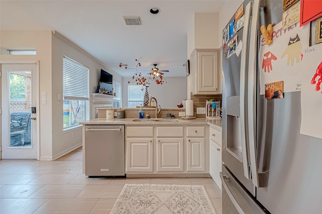 kitchen featuring ceiling fan, tasteful backsplash, kitchen peninsula, sink, and appliances with stainless steel finishes