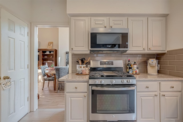 kitchen with light stone counters, white cabinetry, stainless steel appliances, and tasteful backsplash