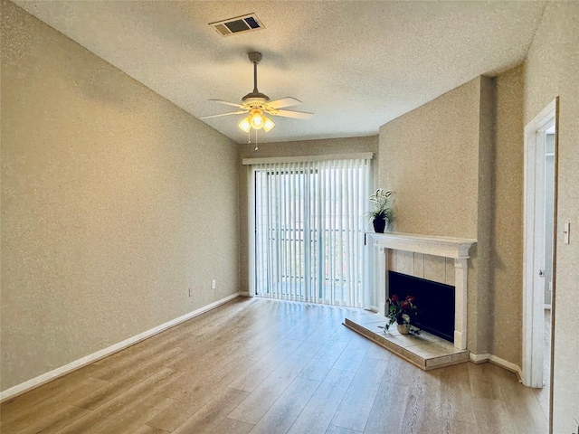 unfurnished living room featuring hardwood / wood-style floors, a fireplace, a textured ceiling, and ceiling fan