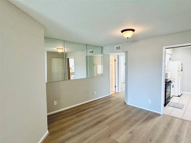 unfurnished room with a textured ceiling and light hardwood / wood-style floors