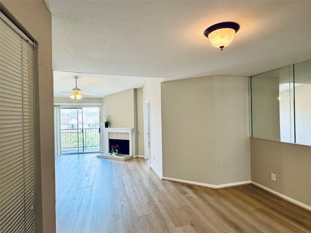 unfurnished living room featuring a fireplace, hardwood / wood-style floors, ceiling fan, and a textured ceiling