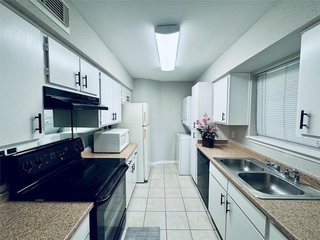 kitchen with black appliances, washer / dryer, white cabinetry, light tile patterned floors, and sink