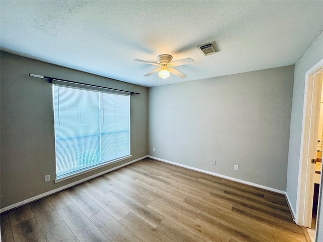 unfurnished room with a textured ceiling, wood-type flooring, and ceiling fan