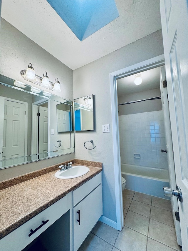 full bathroom featuring toilet, tile patterned flooring, tiled shower / bath, vanity, and a skylight