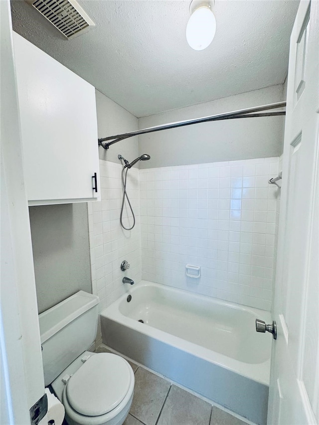 bathroom with toilet, tiled shower / bath, a textured ceiling, and tile patterned flooring