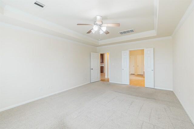 unfurnished bedroom featuring light colored carpet, ceiling fan, crown molding, and a tray ceiling