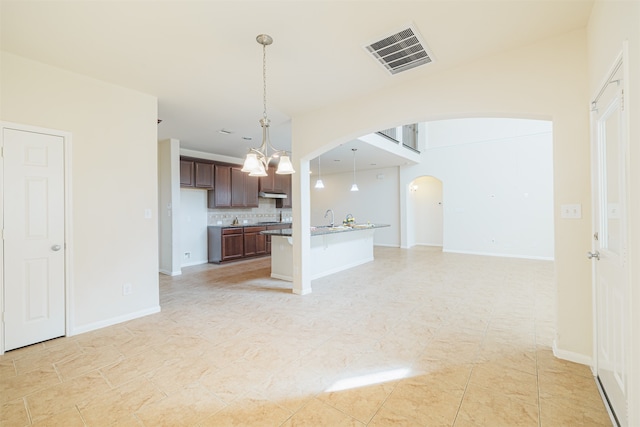 kitchen with an inviting chandelier, sink, dark brown cabinets, backsplash, and pendant lighting