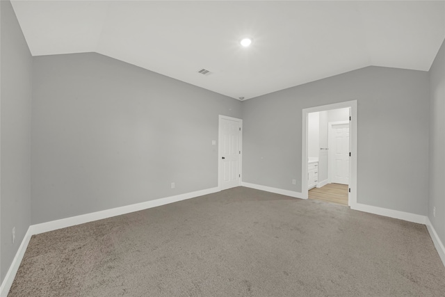 unfurnished bedroom with vaulted ceiling, light colored carpet, and ensuite bath