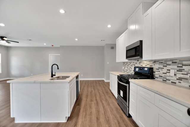 kitchen featuring white cabinets, a center island with sink, black appliances, and light hardwood / wood-style flooring