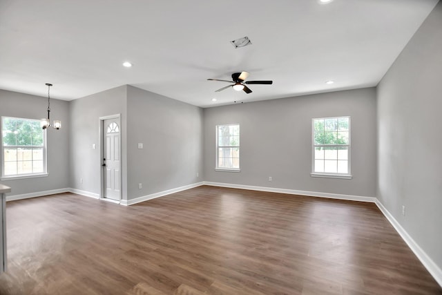 spare room featuring ceiling fan with notable chandelier and dark hardwood / wood-style flooring