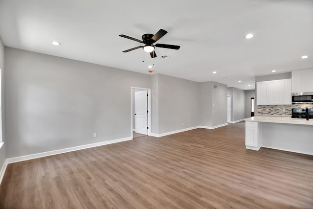 unfurnished living room with wood-type flooring and ceiling fan