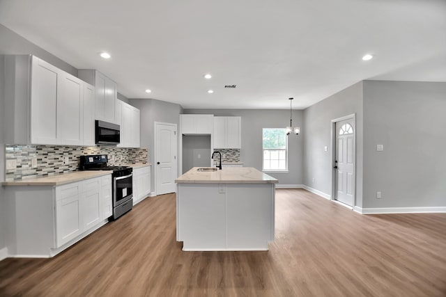 kitchen with an island with sink, white cabinetry, light hardwood / wood-style flooring, and appliances with stainless steel finishes