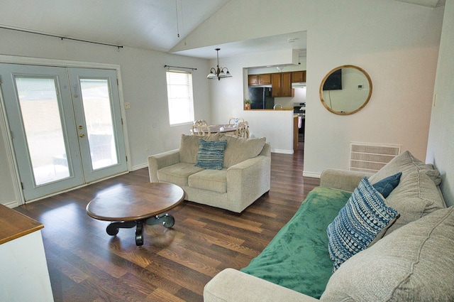 living room with dark wood-type flooring, an inviting chandelier, high vaulted ceiling, and french doors