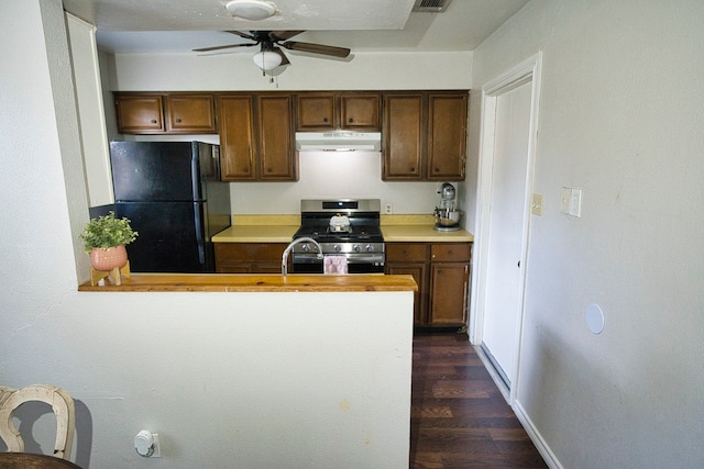 kitchen featuring dark hardwood / wood-style floors, black refrigerator, gas range, kitchen peninsula, and ceiling fan