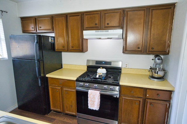 kitchen featuring dark wood-type flooring, black fridge, and gas range