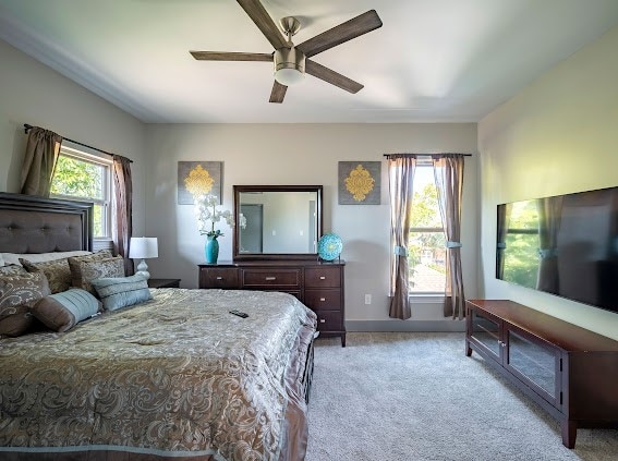 bedroom featuring multiple windows, light colored carpet, and ceiling fan