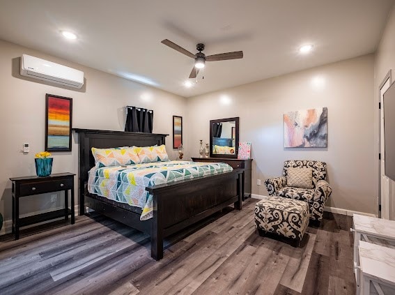 bedroom featuring an AC wall unit, hardwood / wood-style floors, and ceiling fan