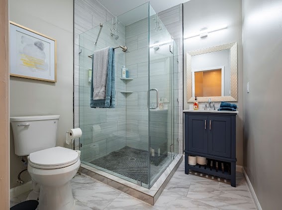 bathroom with a shower with door, vanity, and toilet