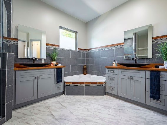 bathroom with a high ceiling, vanity, tile walls, and a tub