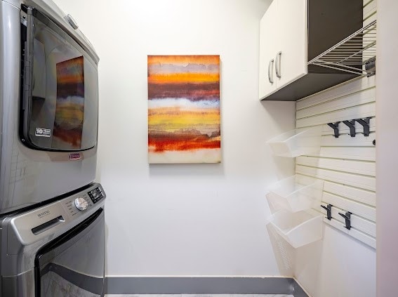 laundry area with cabinets and stacked washer and dryer