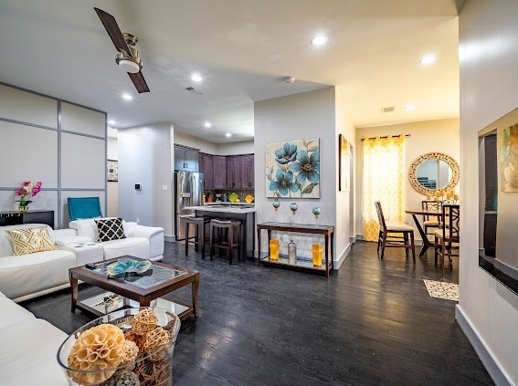 living room featuring ceiling fan and dark hardwood / wood-style floors