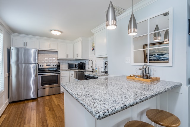 kitchen featuring appliances with stainless steel finishes, decorative light fixtures, dark hardwood / wood-style flooring, white cabinets, and kitchen peninsula