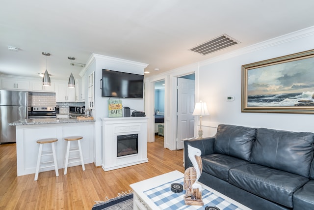 living room featuring light hardwood / wood-style floors and crown molding